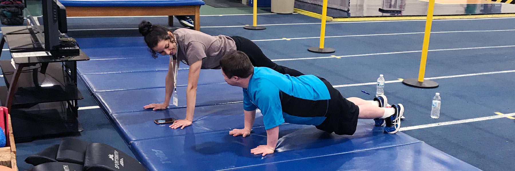An instructor shows an AMP client how to perform a pushup.